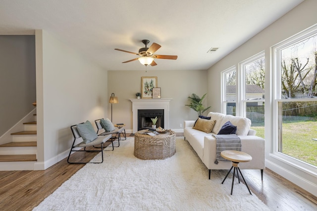 living room featuring stairway, a ceiling fan, wood finished floors, and a fireplace