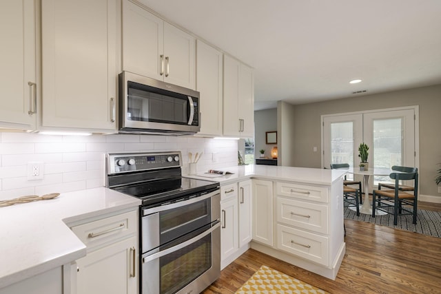 kitchen featuring light wood finished floors, appliances with stainless steel finishes, a peninsula, and light countertops