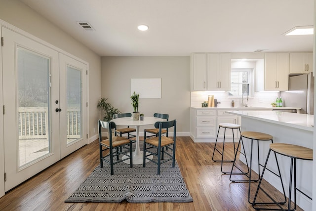 dining room with visible vents, french doors, baseboards, and wood finished floors