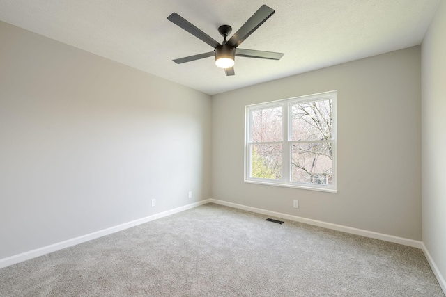 carpeted empty room featuring visible vents, a textured ceiling, baseboards, and a ceiling fan