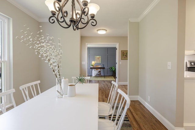 dining area with an inviting chandelier, crown molding, wood finished floors, and baseboards