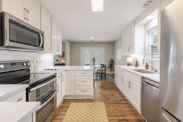 kitchen featuring light wood-type flooring, visible vents, a sink, stainless steel appliances, and light countertops