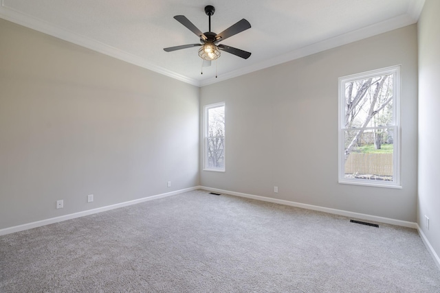 spare room with baseboards, visible vents, ceiling fan, crown molding, and carpet flooring