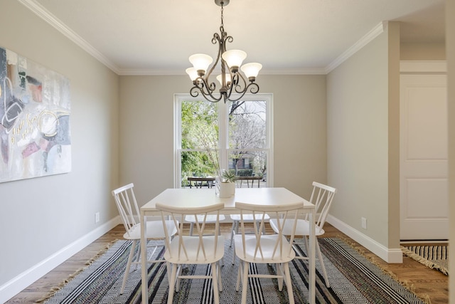 dining room with crown molding, wood finished floors, baseboards, and a chandelier