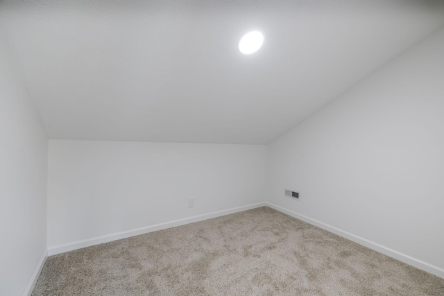 additional living space with visible vents, baseboards, carpet, and vaulted ceiling