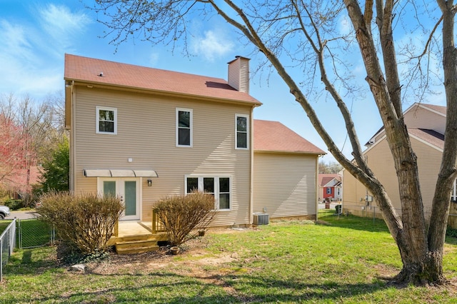 rear view of house featuring fence, a yard, a wooden deck, central AC unit, and a chimney