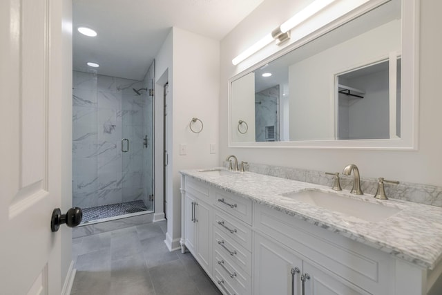 bathroom with a marble finish shower, double vanity, baseboards, and a sink