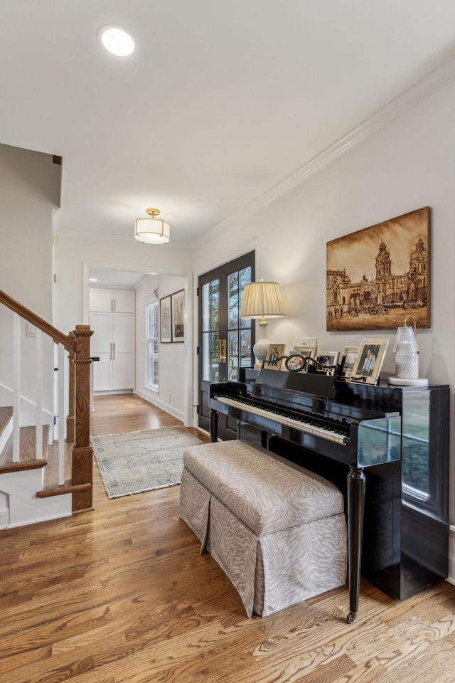 living area featuring baseboards, wood finished floors, ornamental molding, and stairs