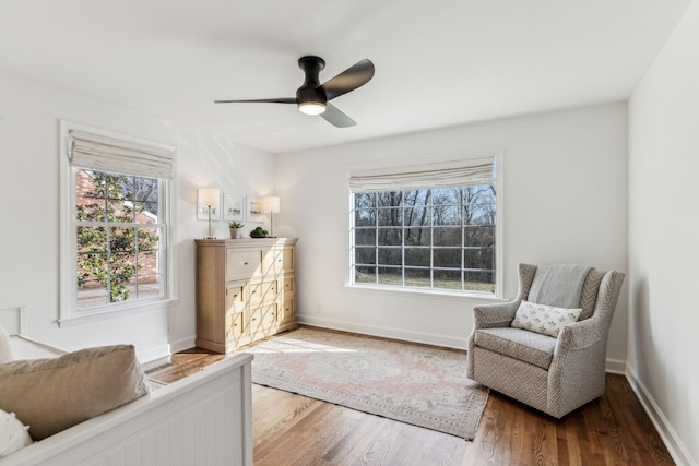 living area featuring baseboards, ceiling fan, and wood finished floors