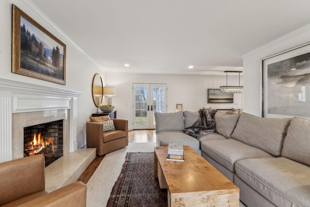 living area with recessed lighting, wood finished floors, a high end fireplace, and ornamental molding