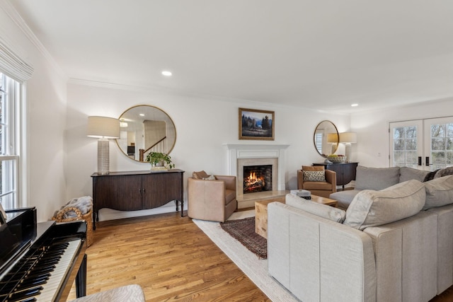 living room featuring ornamental molding, recessed lighting, light wood-type flooring, and a premium fireplace