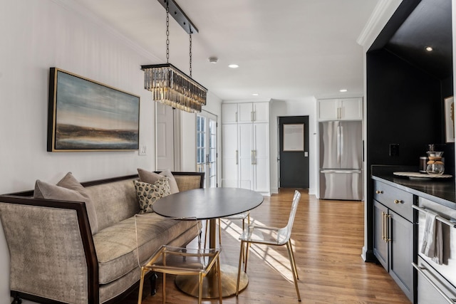 dining room featuring light wood finished floors, a chandelier, recessed lighting, and crown molding