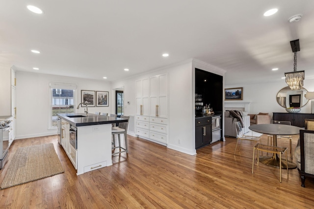 kitchen with dark countertops, white cabinets, and wood finished floors