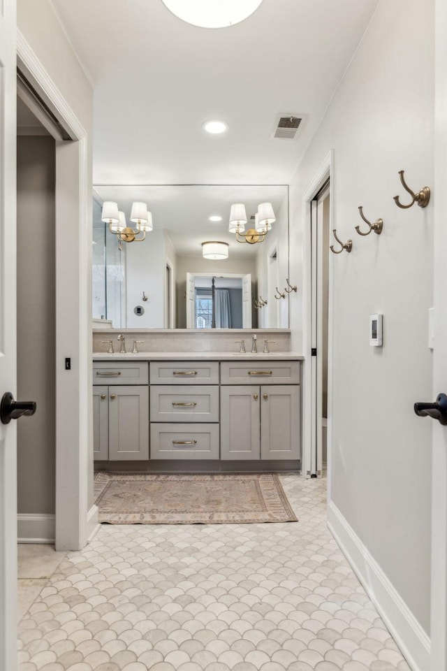 full bathroom featuring double vanity, a notable chandelier, visible vents, and a sink