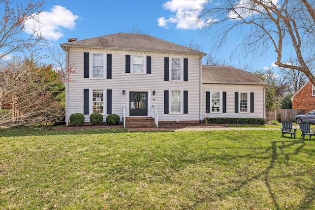 colonial house with a chimney, roof with shingles, a front lawn, and fence