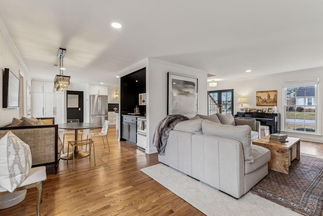 living area with recessed lighting, an inviting chandelier, wood finished floors, and ornamental molding