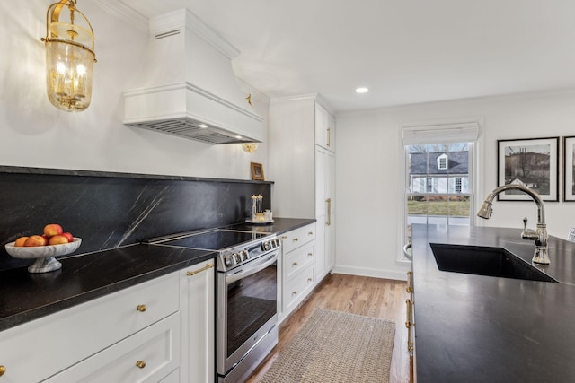 kitchen featuring stainless steel electric stove, a sink, custom range hood, white cabinets, and light wood-type flooring