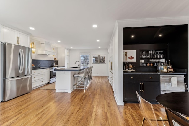 kitchen featuring dark countertops, light wood finished floors, premium range hood, stainless steel appliances, and white cabinetry