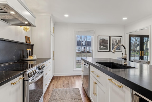 kitchen with dark countertops, appliances with stainless steel finishes, custom range hood, and a sink