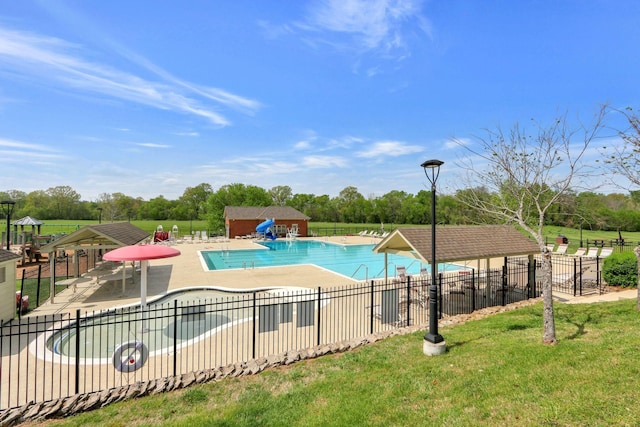 pool with a yard, a patio area, fence, and a water slide