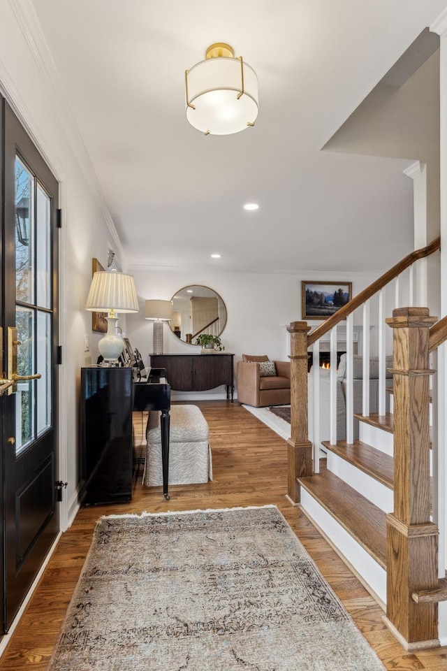 foyer entrance featuring wood finished floors, recessed lighting, arched walkways, ornamental molding, and stairs