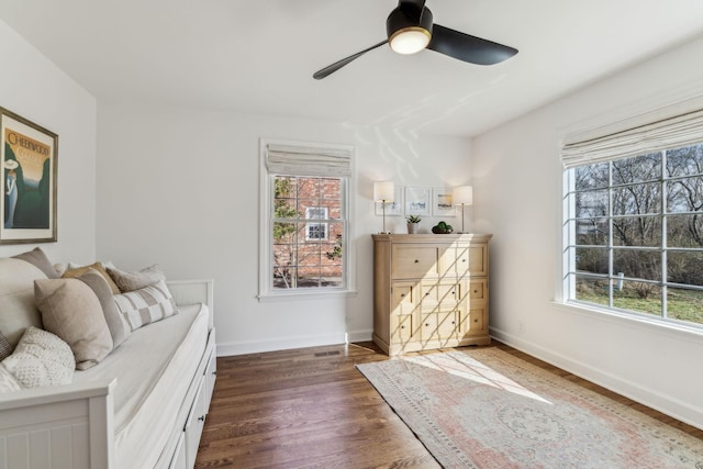 living area featuring dark wood-style floors, baseboards, a wealth of natural light, and ceiling fan