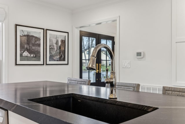 interior details featuring dark countertops, ornamental molding, white cabinetry, and a sink