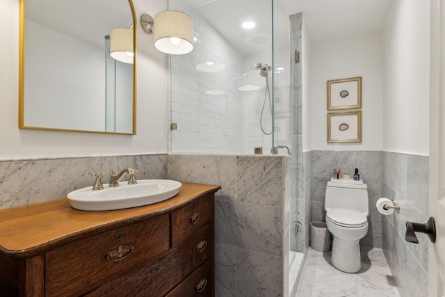 full bath featuring a shower stall, a wainscoted wall, toilet, vanity, and tile walls