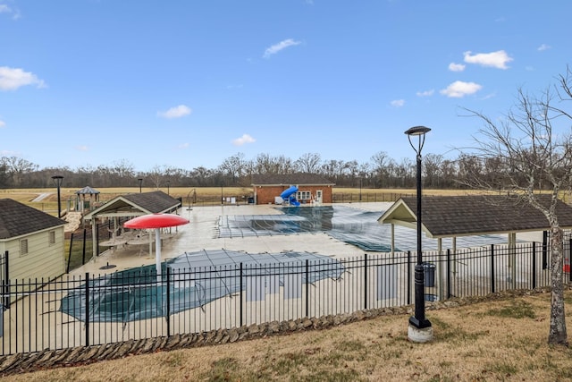 pool featuring a patio area, fence, and an outbuilding