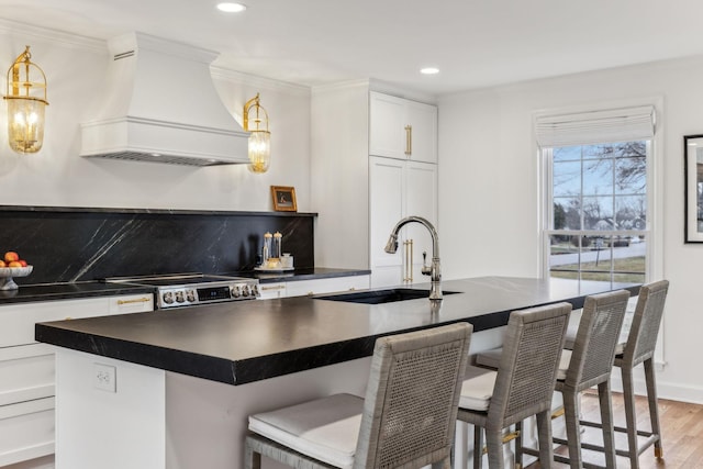 kitchen featuring dark countertops, stainless steel range with electric cooktop, custom range hood, and a sink