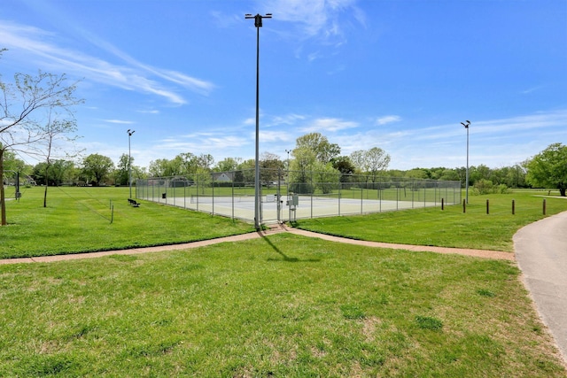 view of community with a tennis court, a yard, and fence