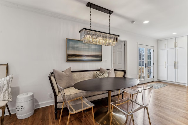 dining space with wood finished floors, baseboards, an inviting chandelier, recessed lighting, and ornamental molding