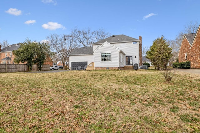 rear view of house featuring a yard, a chimney, a garage, and fence