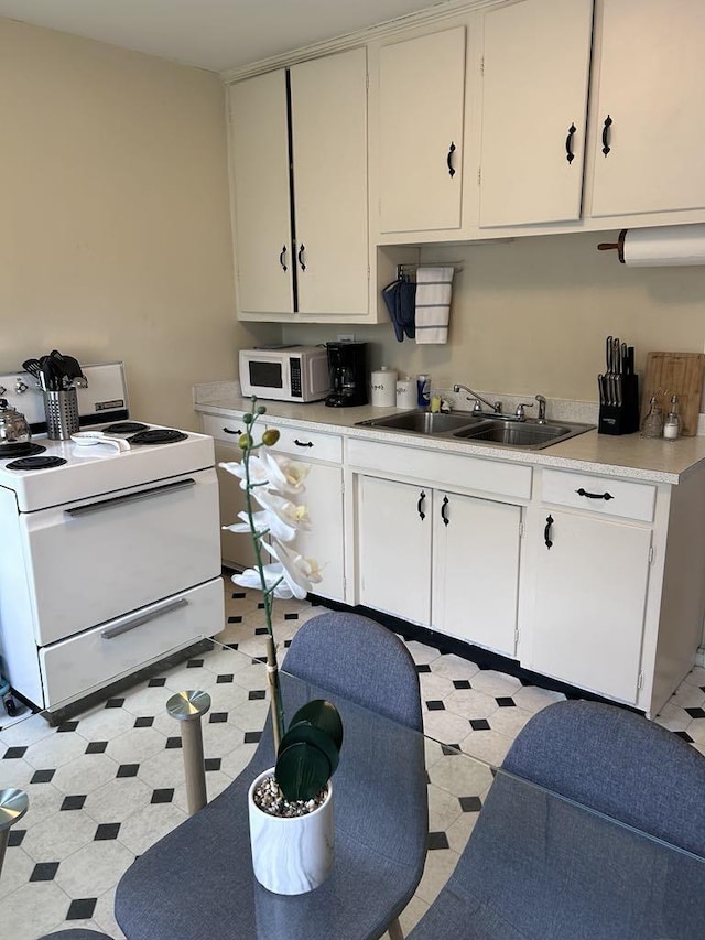 kitchen with a sink, white cabinetry, white appliances, light countertops, and light floors