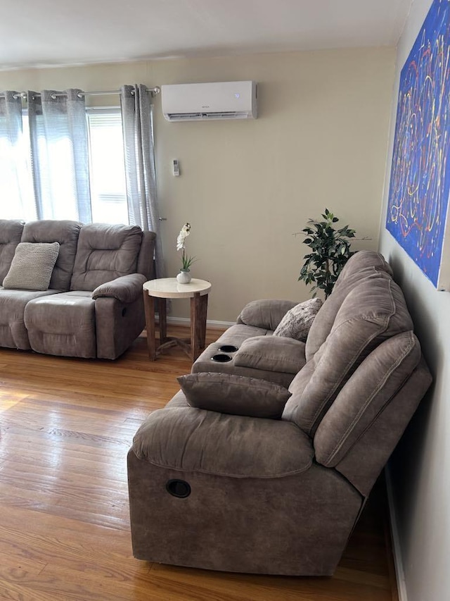 living area featuring wood finished floors, baseboards, and a wall mounted air conditioner