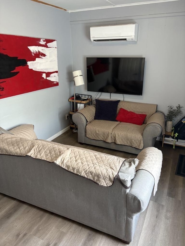 living area featuring baseboards, a wall unit AC, and wood finished floors