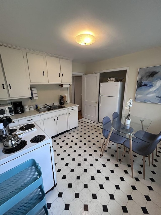 kitchen featuring light floors, light countertops, white appliances, white cabinetry, and a sink