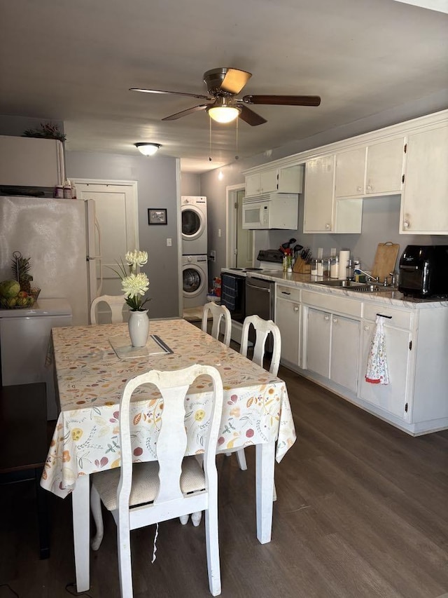 dining space with a toaster, stacked washer / drying machine, dark wood-style flooring, and ceiling fan