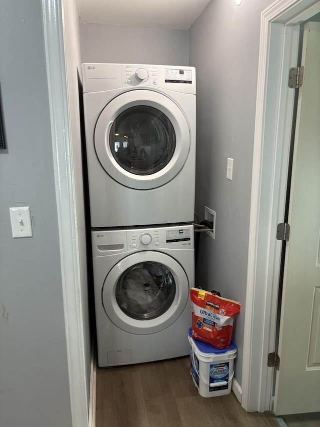 laundry room featuring wood finished floors, laundry area, and stacked washer / dryer