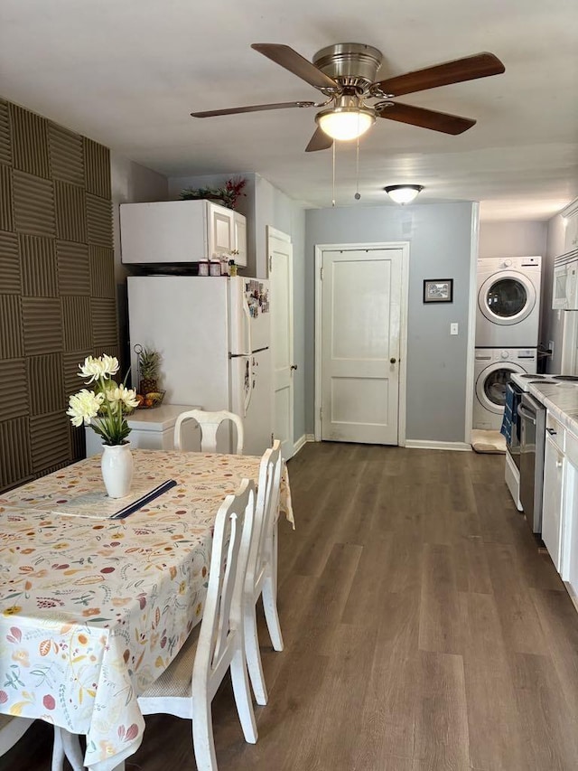 dining space with ceiling fan, baseboards, stacked washer and clothes dryer, and dark wood-style floors