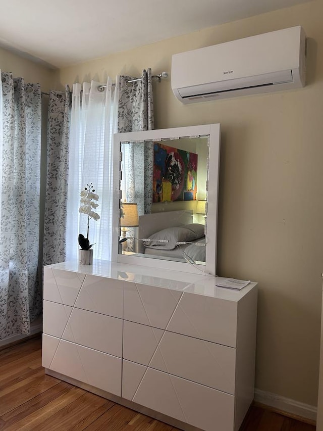 unfurnished bedroom with a wall mounted air conditioner and wood finished floors