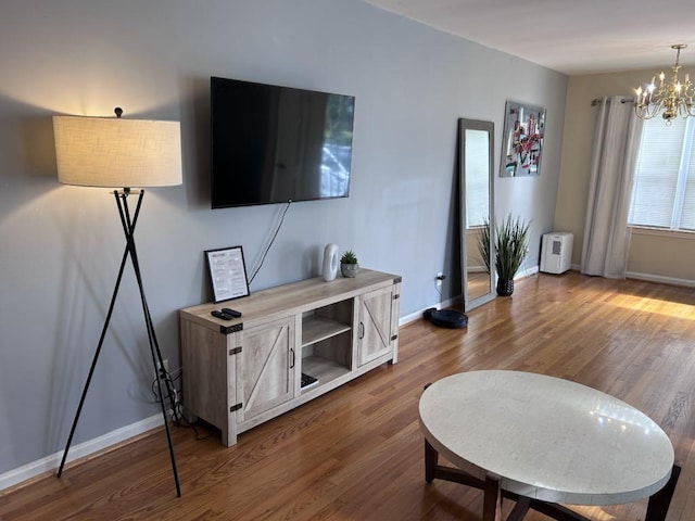 living area featuring baseboards, an inviting chandelier, and wood finished floors