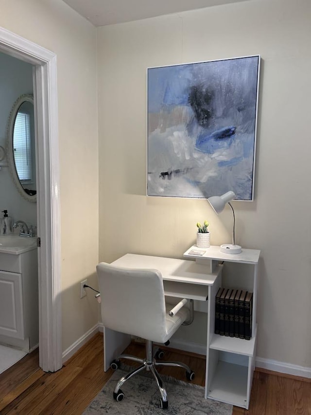 home office with a sink, baseboards, and wood finished floors