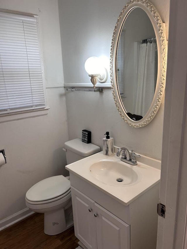 bathroom with toilet, vanity, and wood finished floors