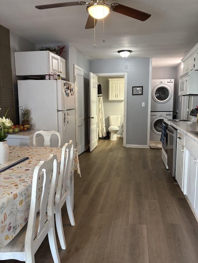 kitchen with ceiling fan, white appliances, dark wood-type flooring, and stacked washing maching and dryer