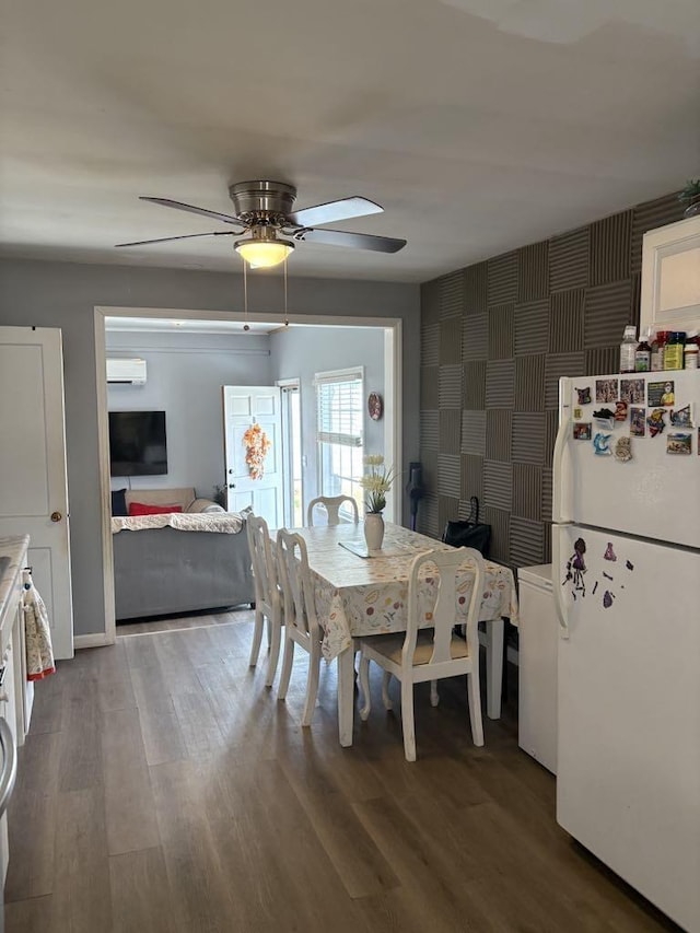 dining space with ceiling fan, an AC wall unit, wood finished floors, and wallpapered walls