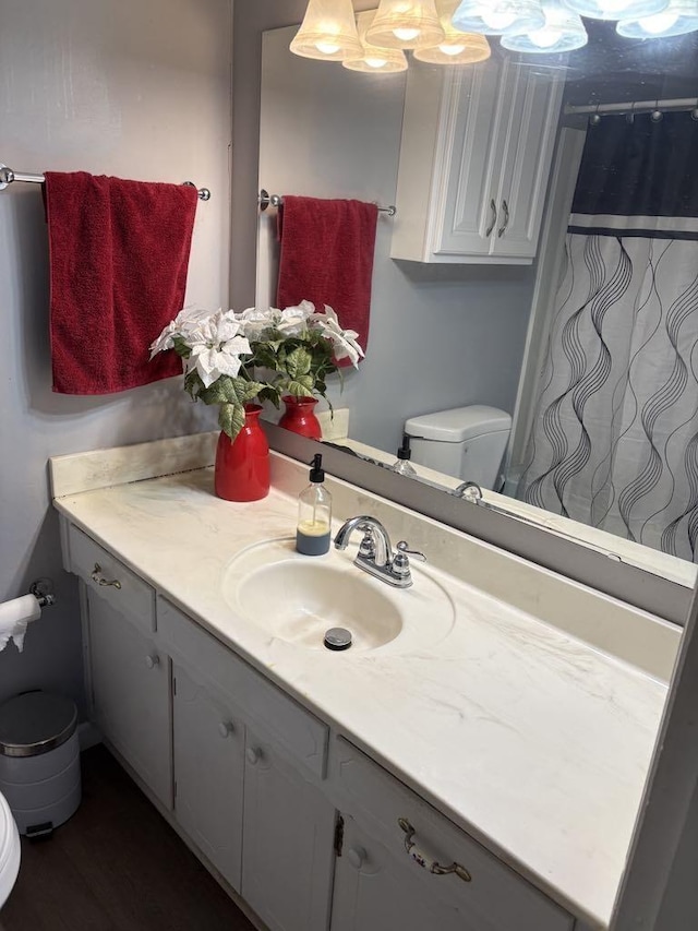 bathroom with toilet, a chandelier, and vanity