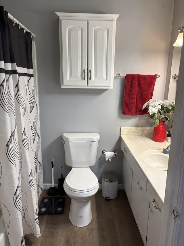 bathroom featuring curtained shower, toilet, wood finished floors, and vanity