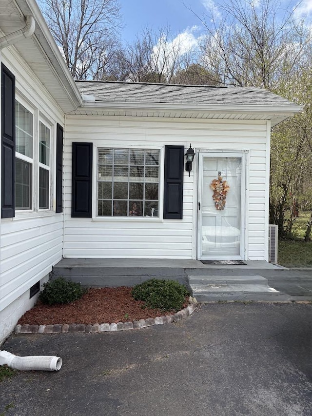 view of exterior entry with a shingled roof