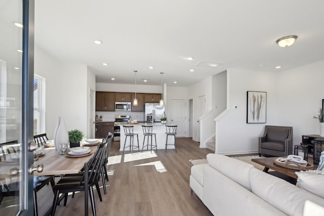 living room with recessed lighting, light wood-type flooring, baseboards, and stairway